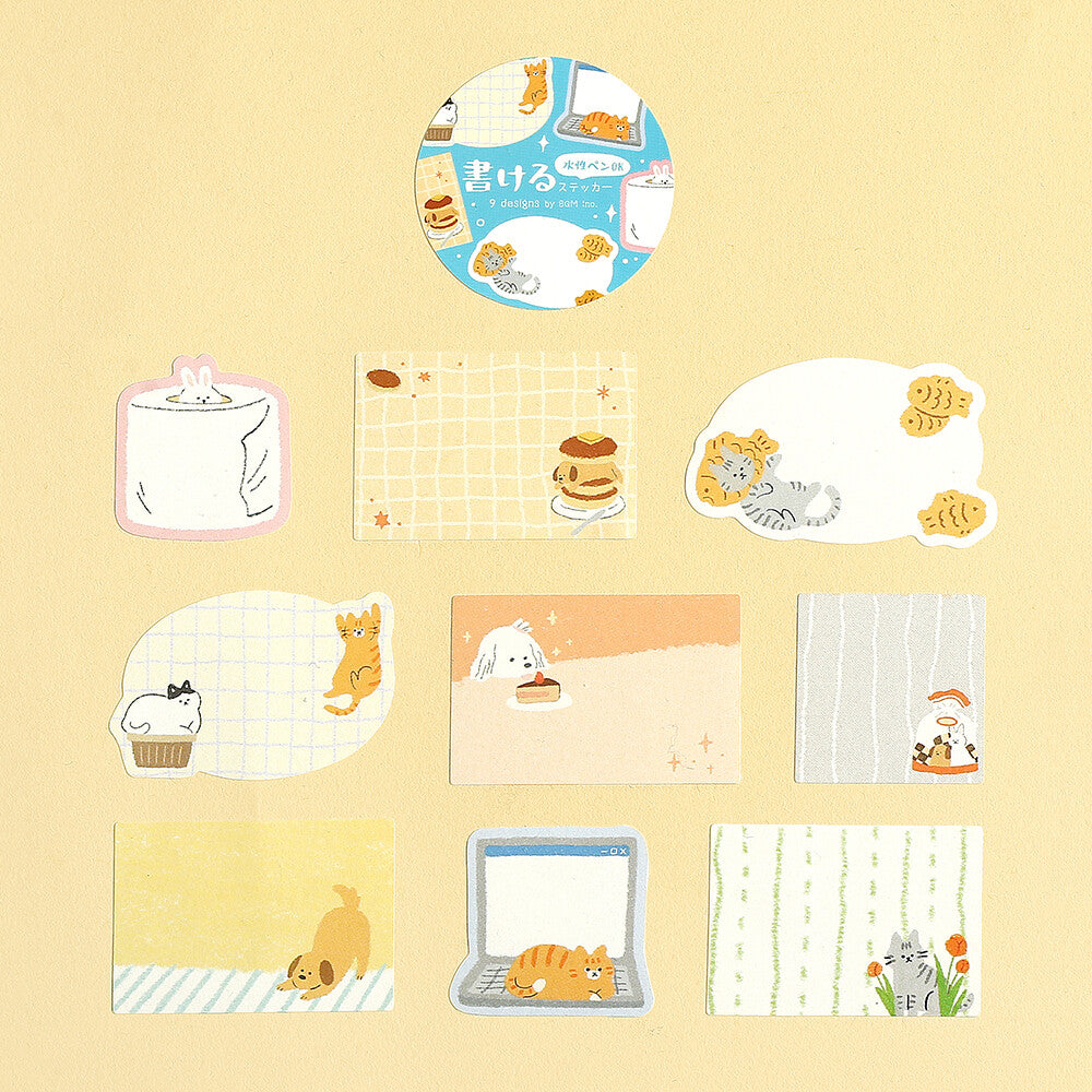 A set of cute illustrated stationery pieces arranged on a pale yellow background, including a round sticker, cards, and small note-like sheets with cat and food drawings.