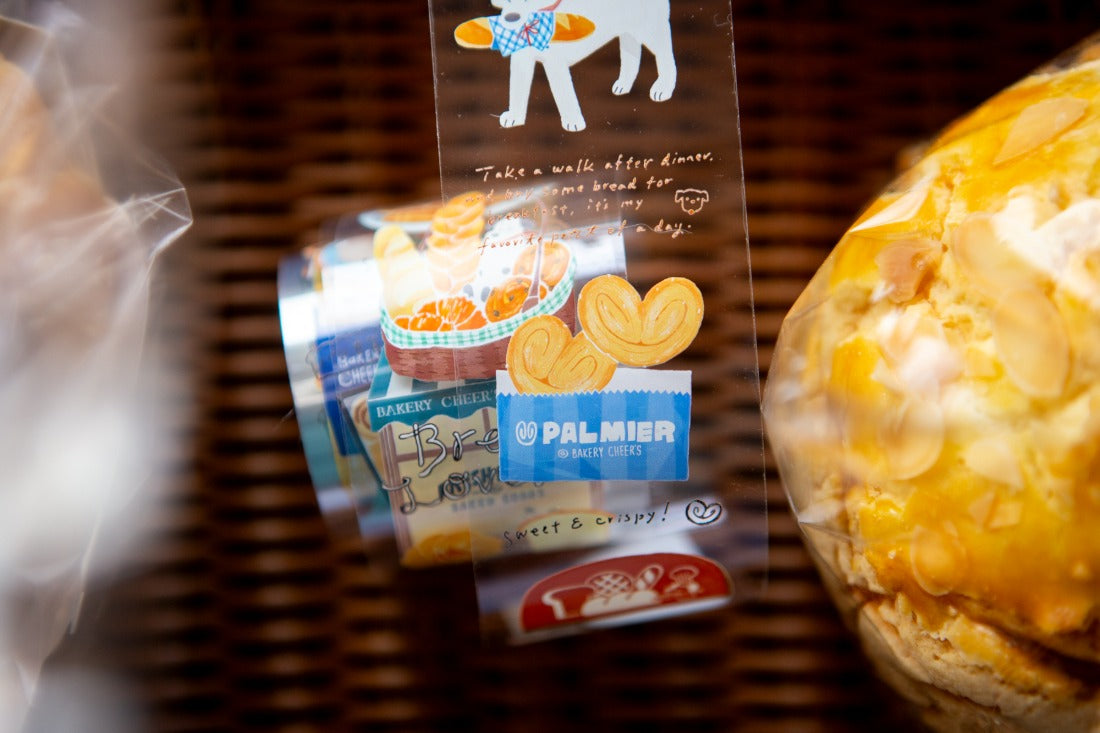 Packaged cookies with a Palmera brand label next to a bread roll on a textured surface.