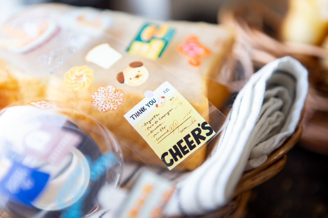 Gift basket with a plush toy, wrapped items, and a 'Thank You' card with 'Cheers' text.