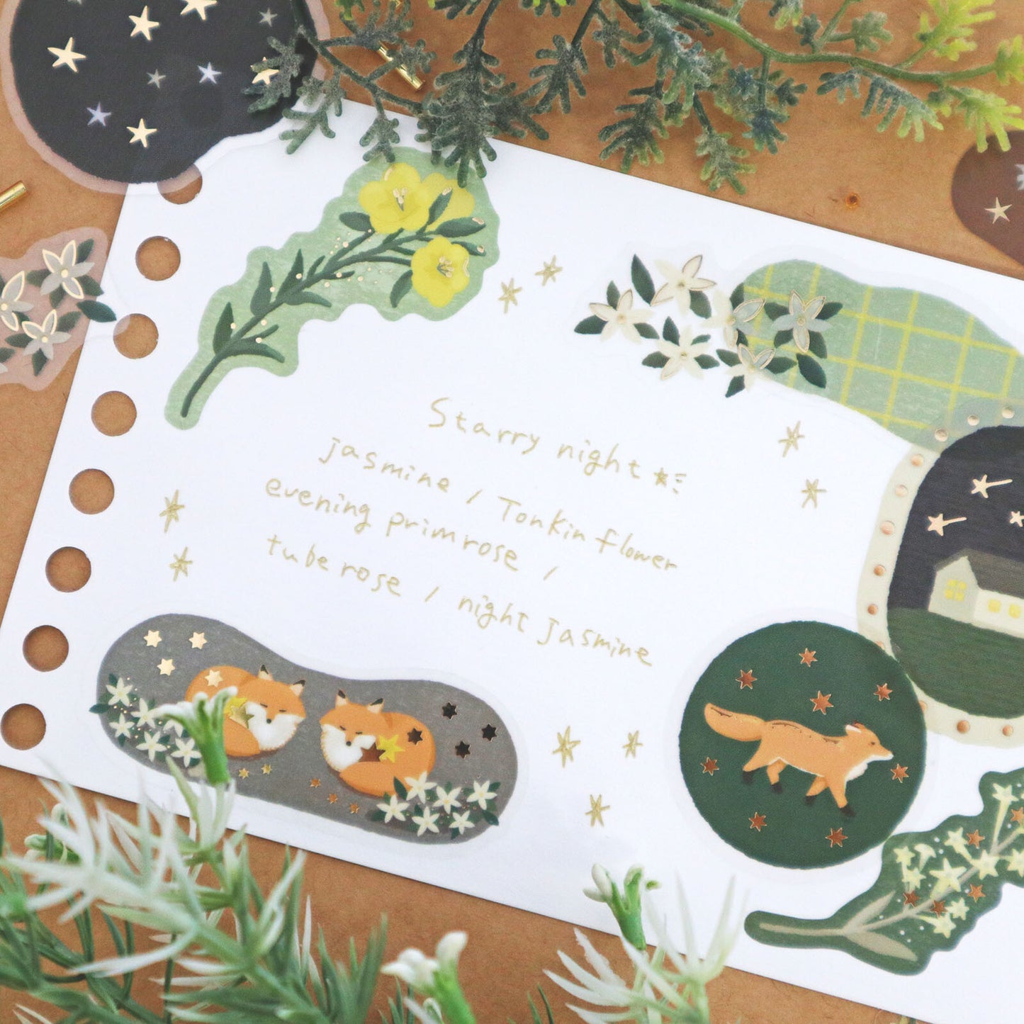 Set of decorative stickers with foxes, flowers, and moon on a wooden surface.