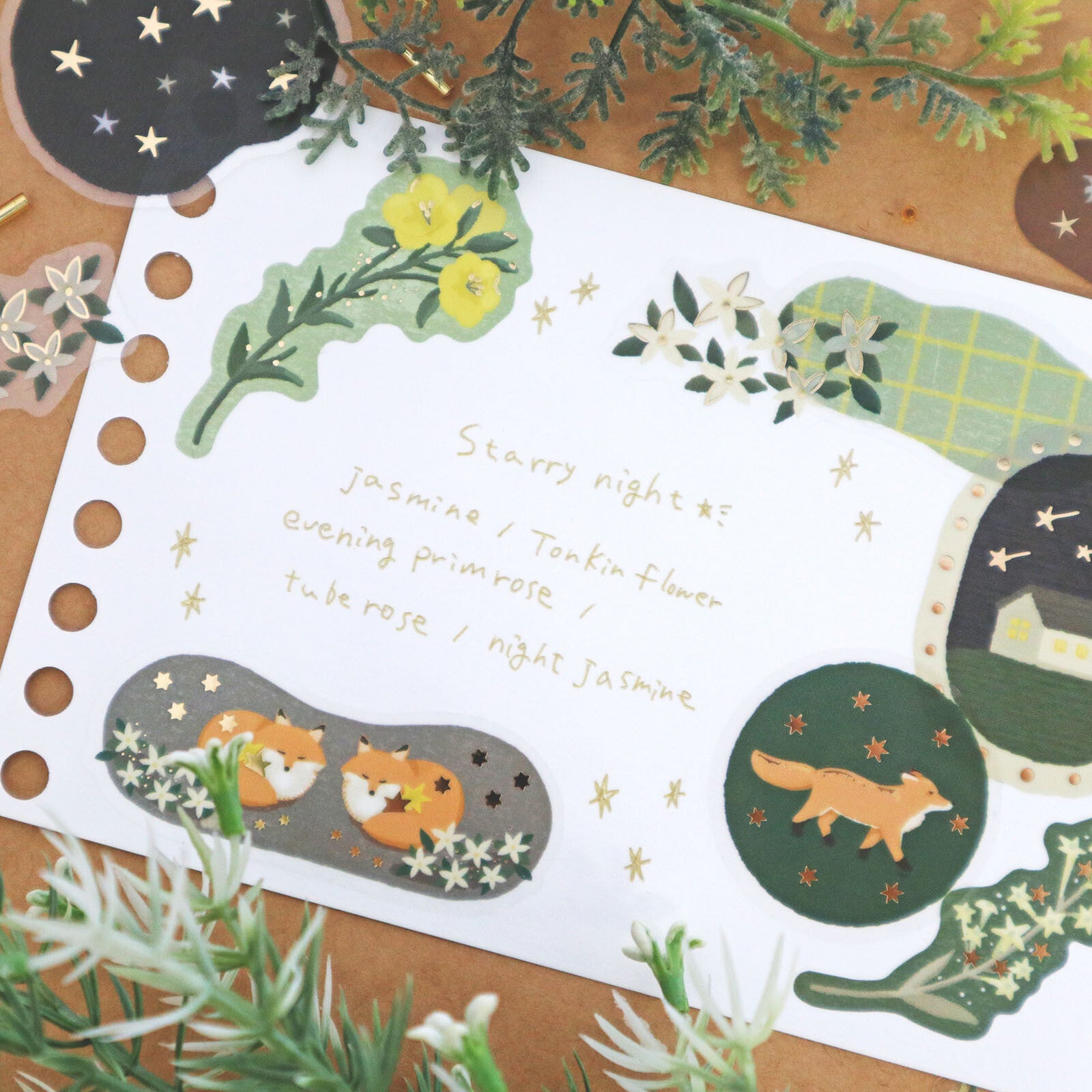 Set of decorative stickers with foxes, flowers, and moon on a wooden surface.