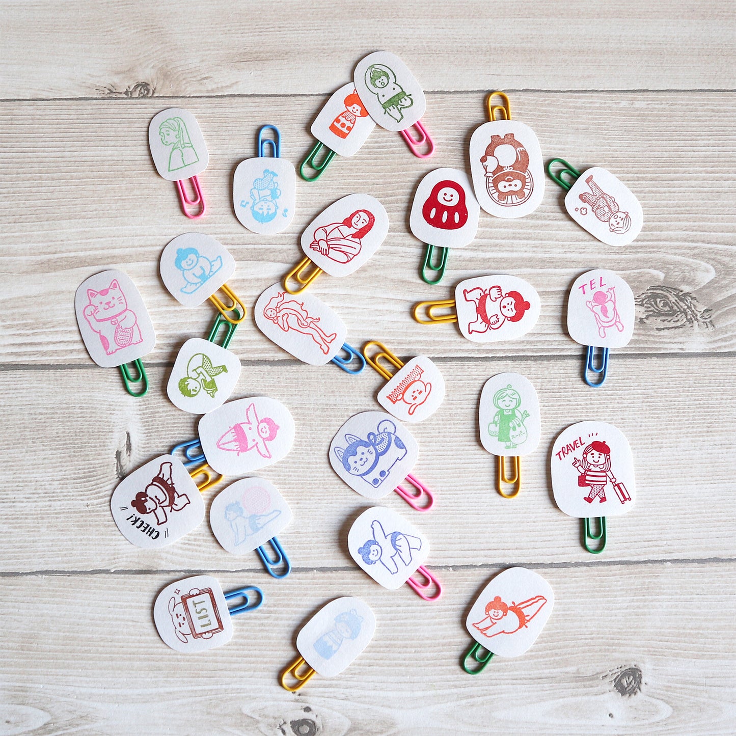 Colorful paper clips with cartoon designs on a wooden surface