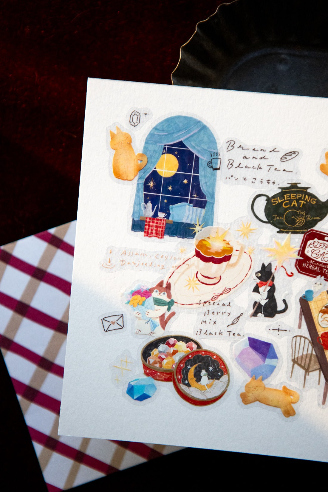 Layered stickers of cats and other night elements on a white paper