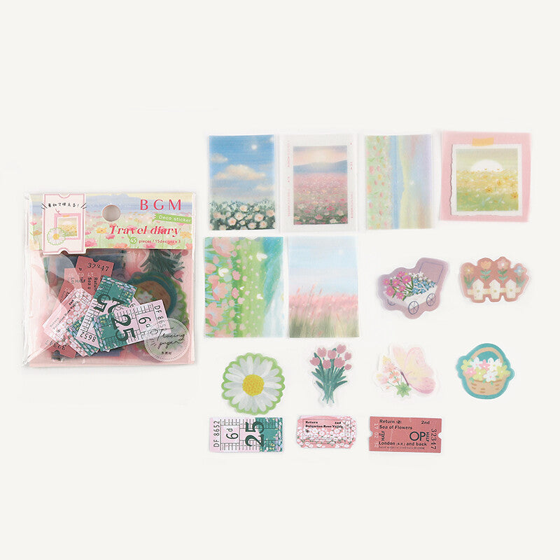 A travel-themed sticker or scrapbook kit displayed on a plain light background, including a packaged set of postcard-style pieces labeled 'BGM Travel diary' and several loose decorative elements such as floral cards, ticket stickers, daisy, tulip, basket, and pastel illustration pieces.
