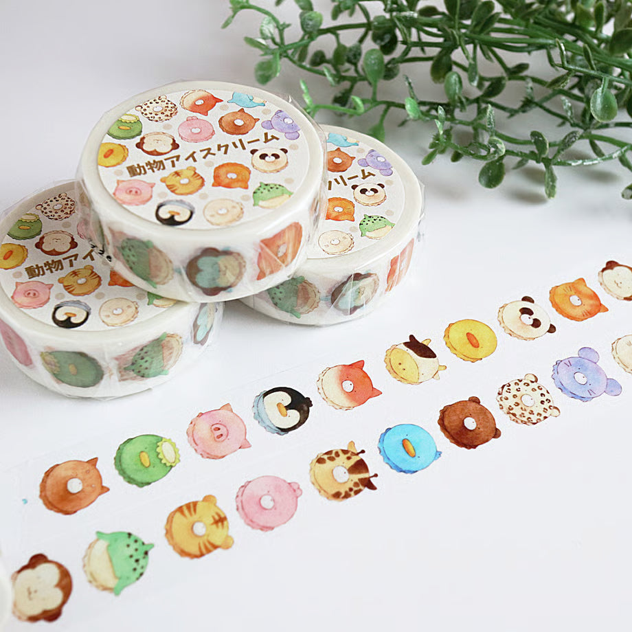 Three rolls of decorative tape with animal-themed designs on a white surface with greenery in the background.