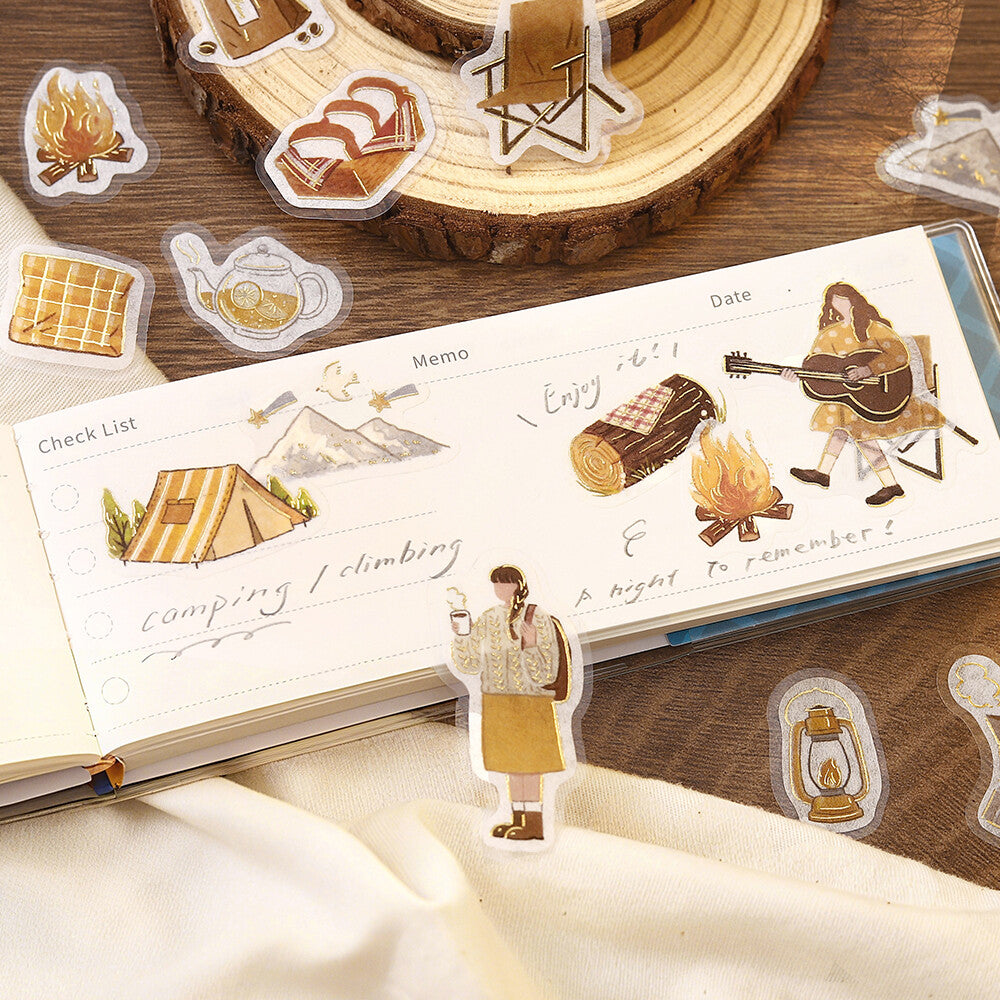 Sticker set with camping and outdoor-themed designs on a wooden surface.