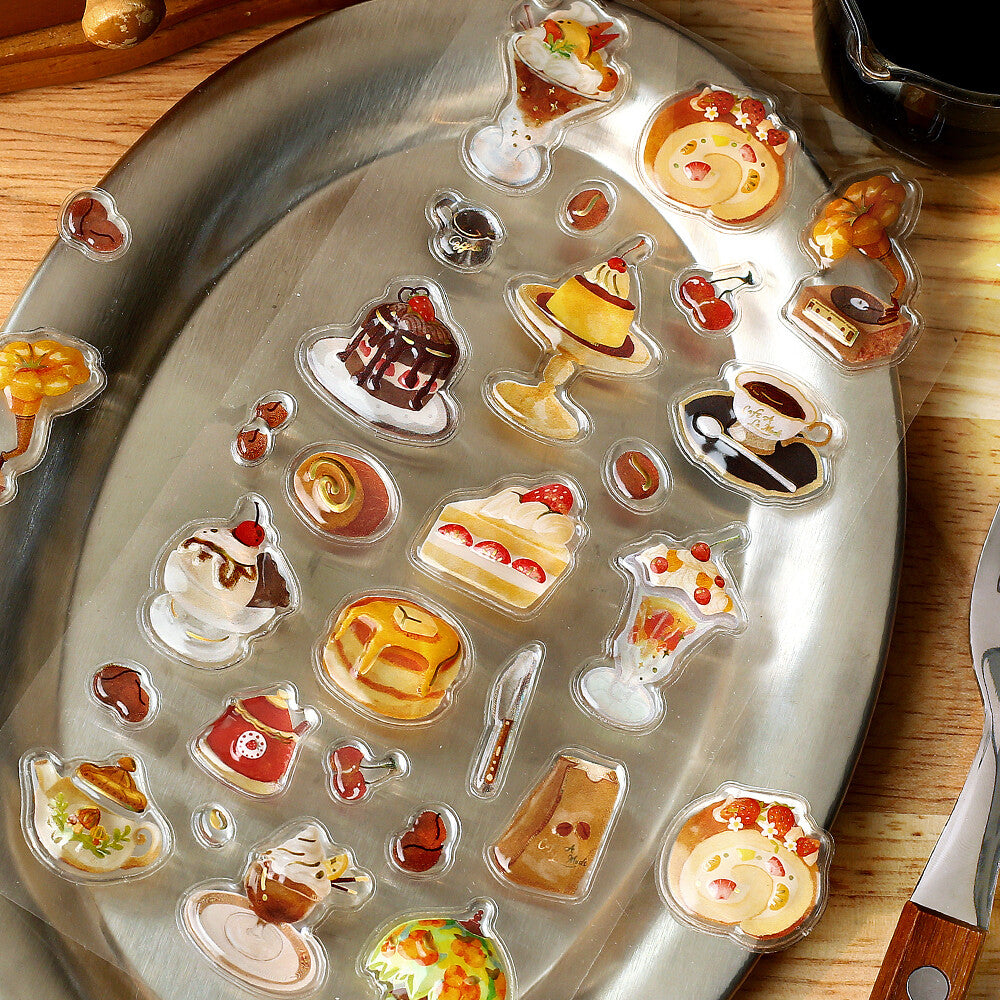 Metal tray with various food-themed decorative stickers on a wooden surface.