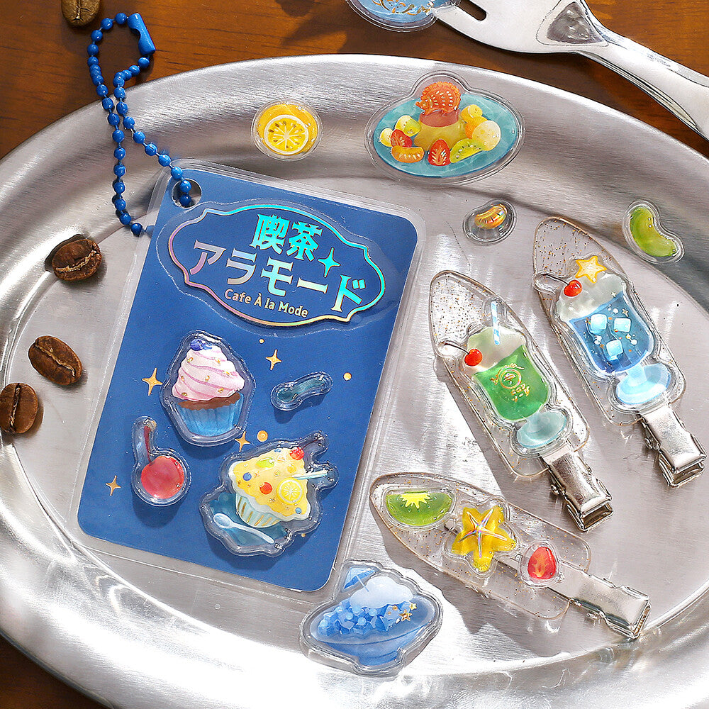 Decorative clips shaped like desserts on a metal tray with a blue card.