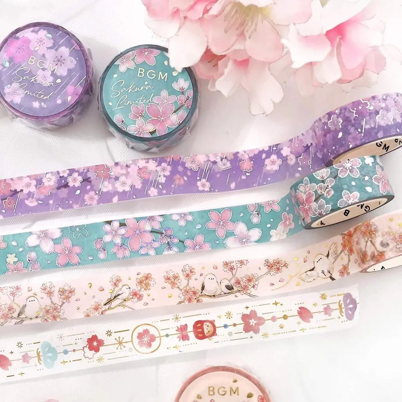 Decorative washi tape with floral and animal designs on a white surface with flowers.