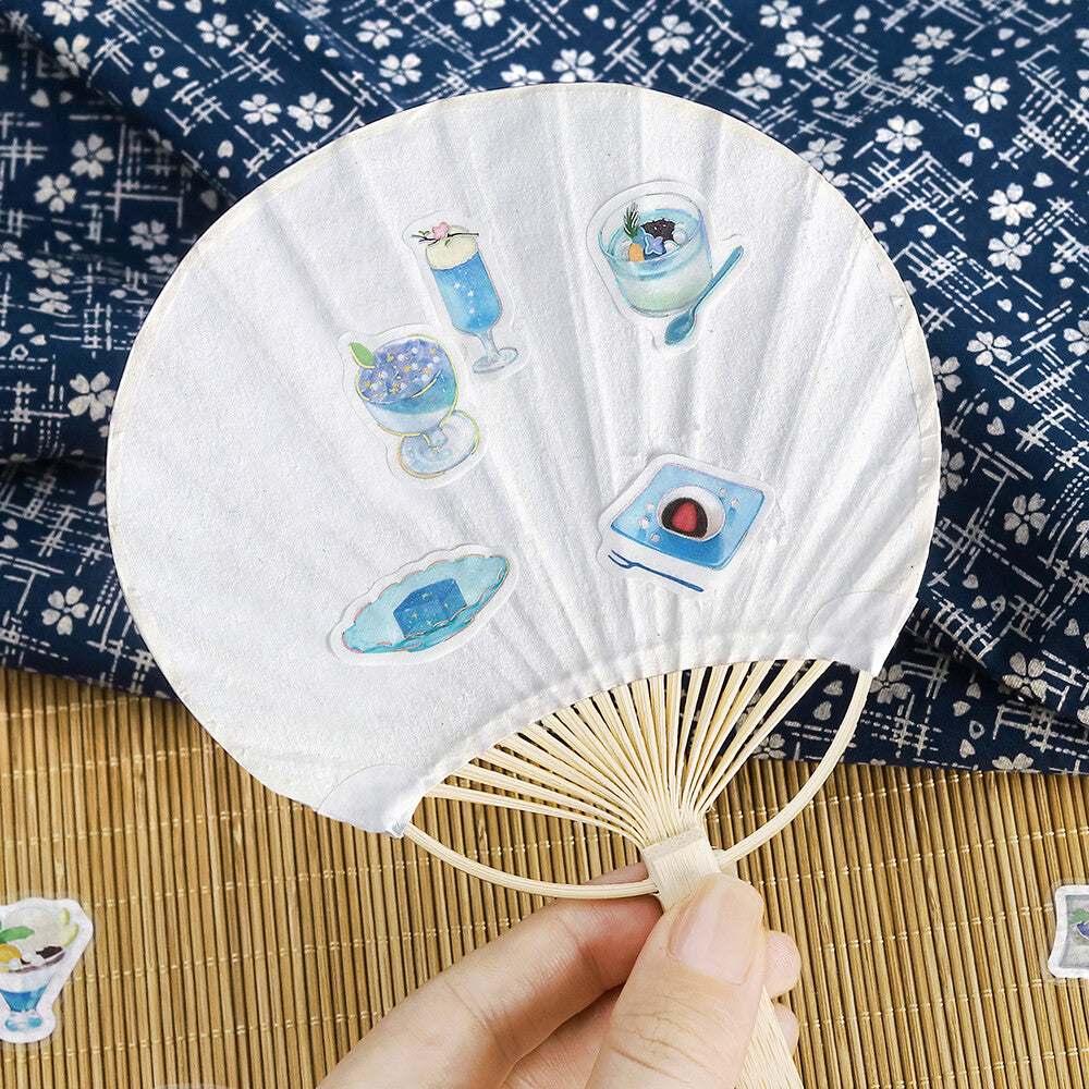 Handheld fan with decorative stickers on a patterned fabric background