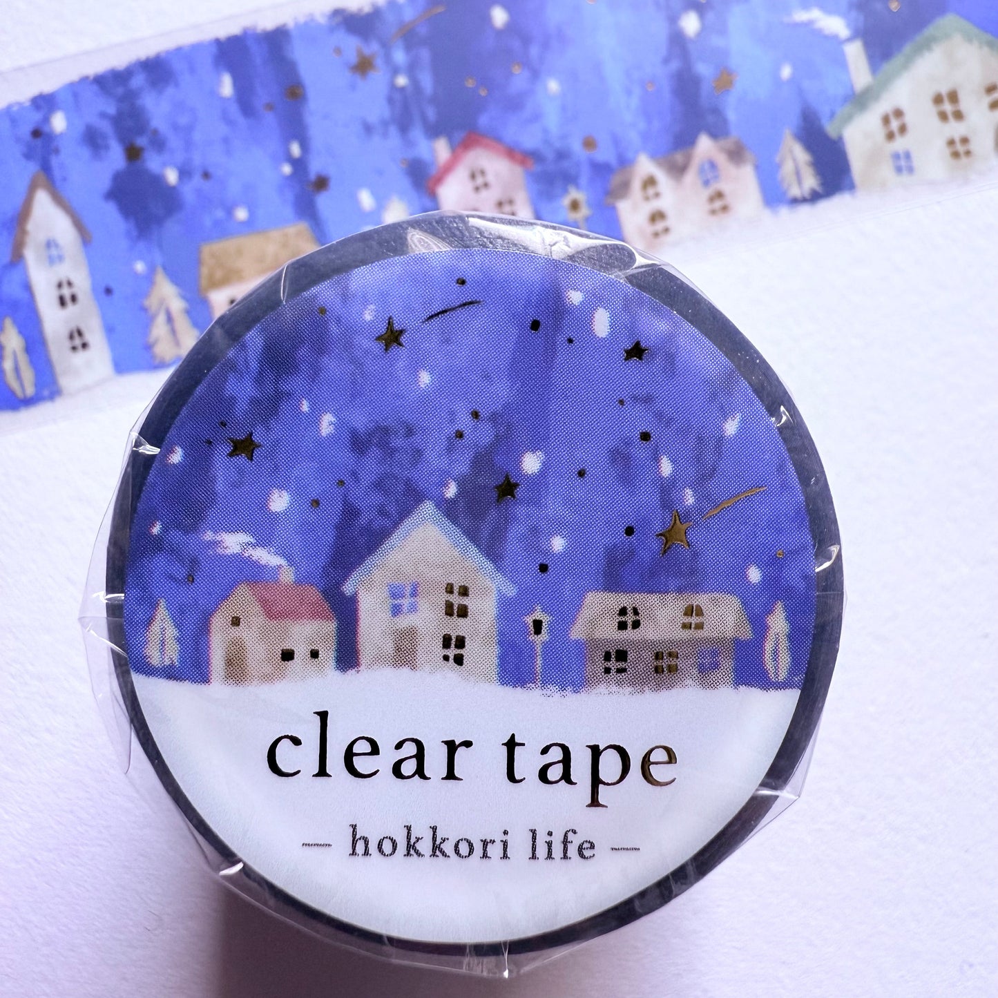 Clear tape with a decorative label featuring small houses and stars on a blue background.