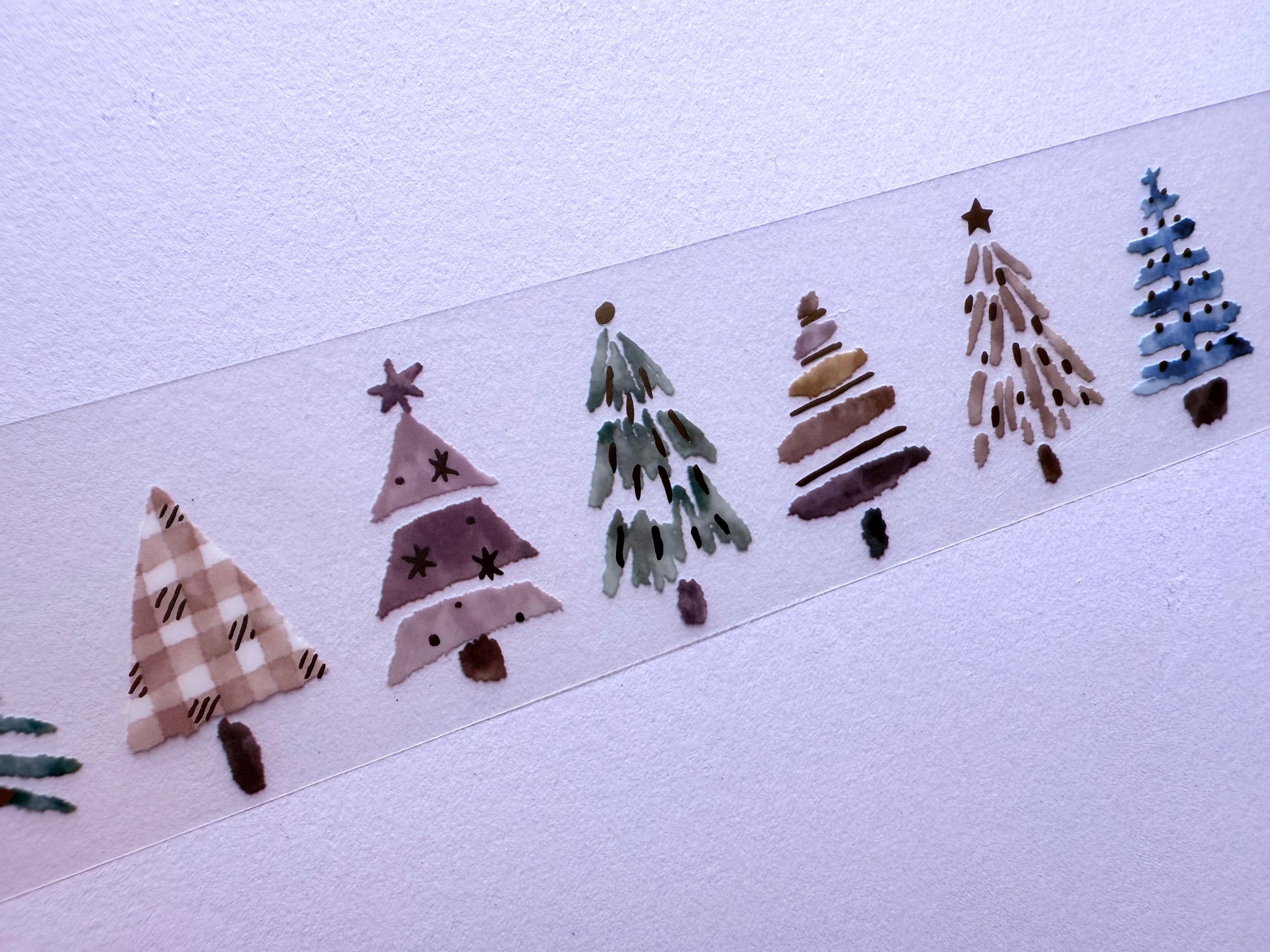 Decorative strip with hand-painted Christmas tree designs on a white background