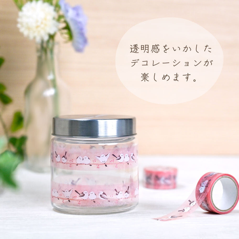 Decorative jar with cherry blossom design on a table with flowers and tape in the background.