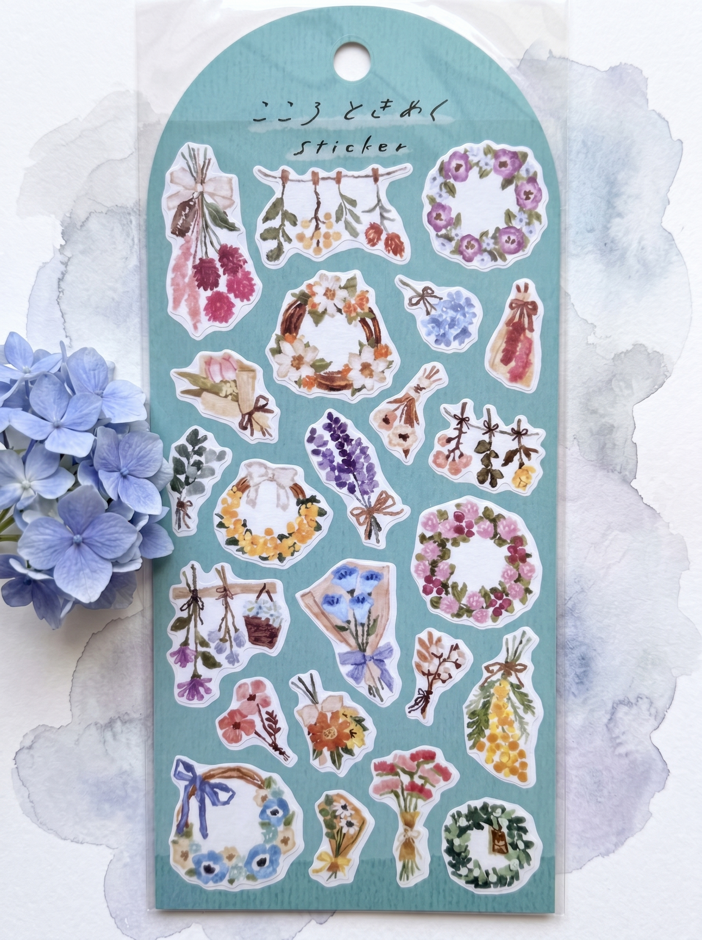 Sheet of decorative stickers with floral designs on a light blue background, surrounded by flowers.
